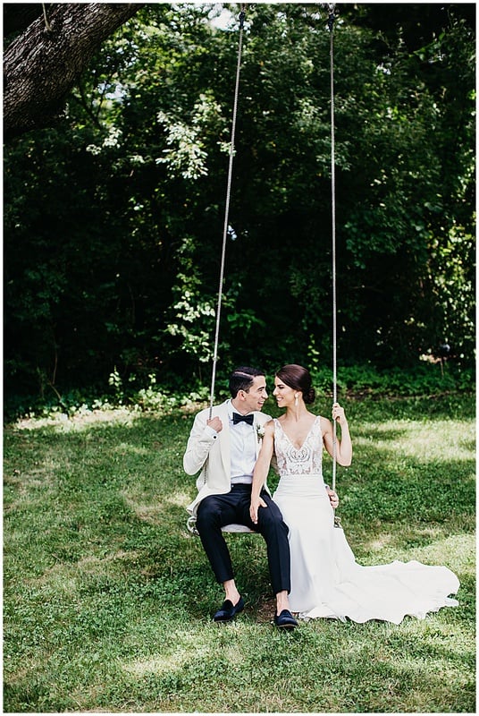 bride and groom sitting on a swinging chair before wedding ceremony