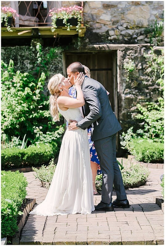 bride and groom kiss at their outdoor wedding ceremony