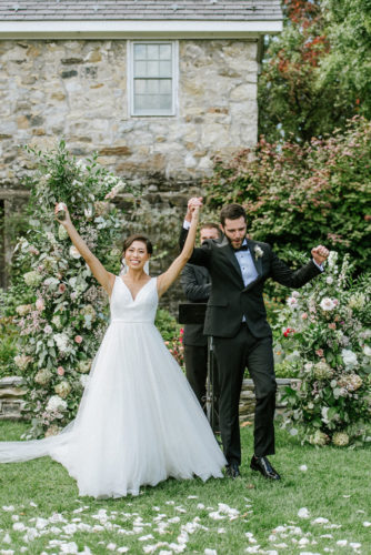 bride and groom raise their arms in celebration