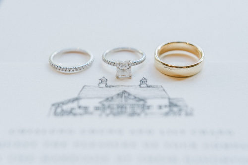 wedding rings displayed on top of the wedding invitation