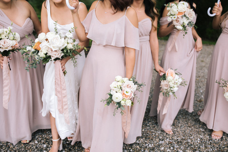 bridesmaids in blush dresses holding bouquets of white and pink flowers