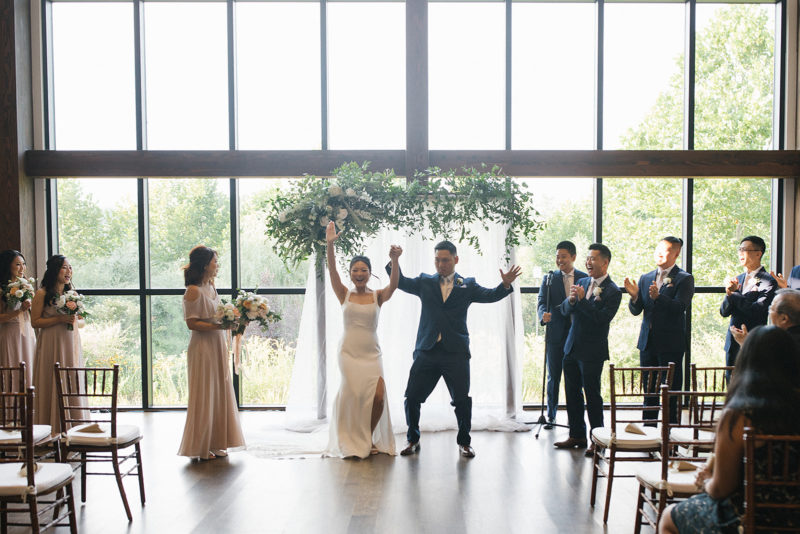 bride and groom with arms up celebrating marriage