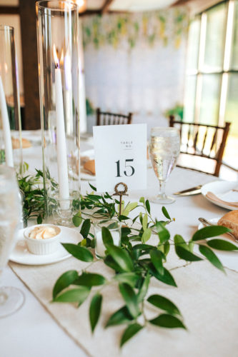 table setup with candles and greenery against white tablecloth