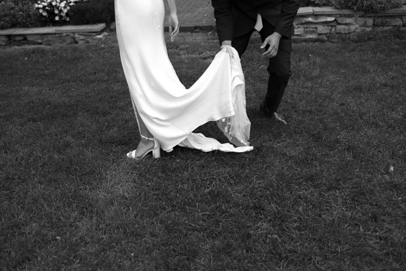 groom helping the bride with her dress in the grass