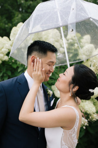 bride and groom embracing under an umbrella