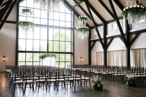 indoor wedding ceremony set up with white flowers and greenery in a farmhouse