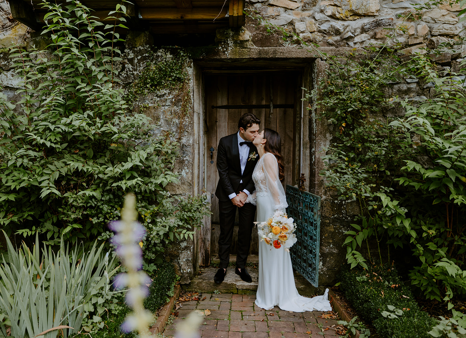 bride and groom share a kiss in an English garden