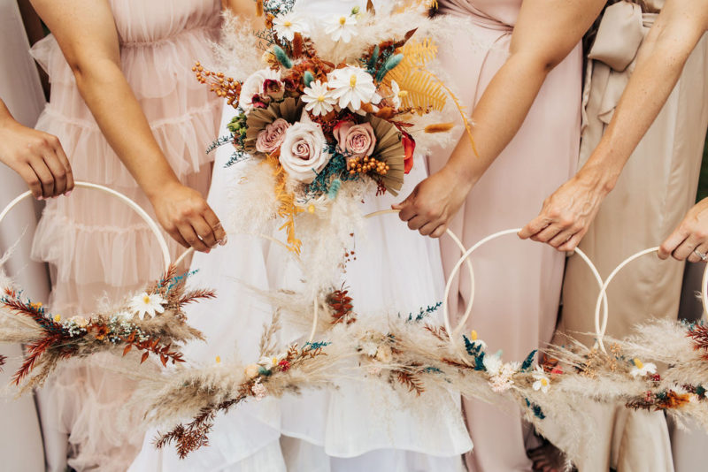 bridesmaids and bride hold out their floral arrangements