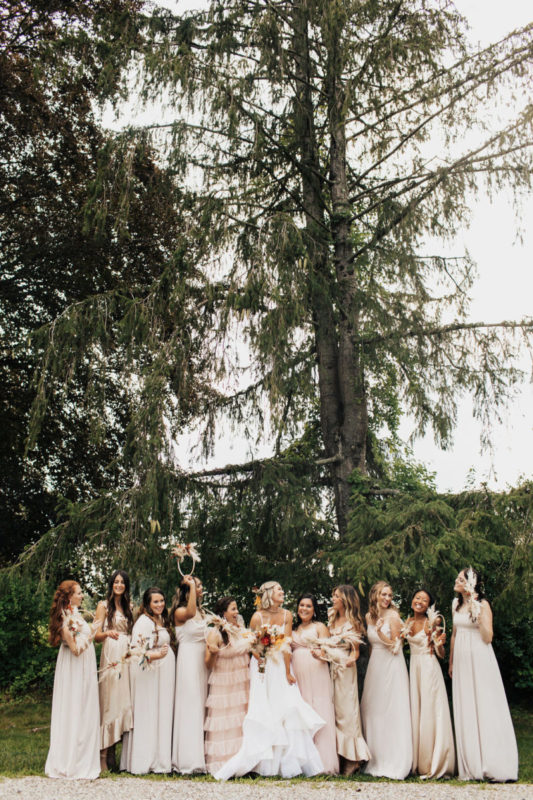 bride and bridesmaids pose in front of trees