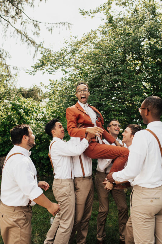groomsmen lift the groom into the air