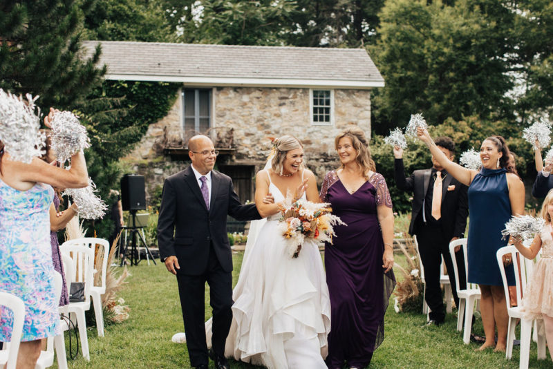 bride walks down the aisle with mother and father