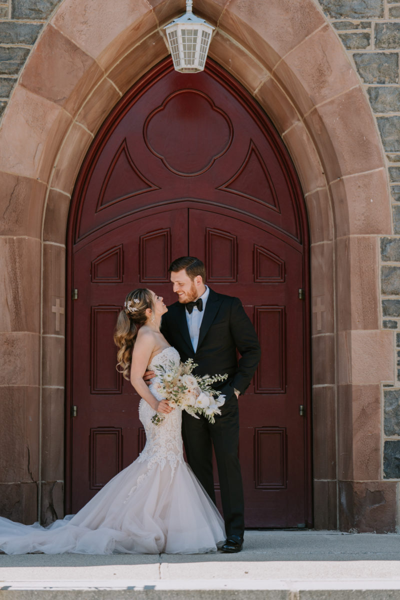 bride and groom pose in front of a church