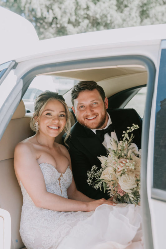 bride and groom in the back of a white car