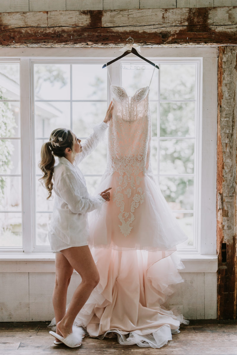 bride looking for wedding dress hanging on the window
