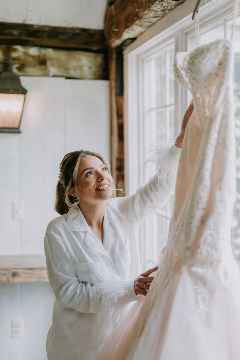bride looking for wedding dress hanging on the window