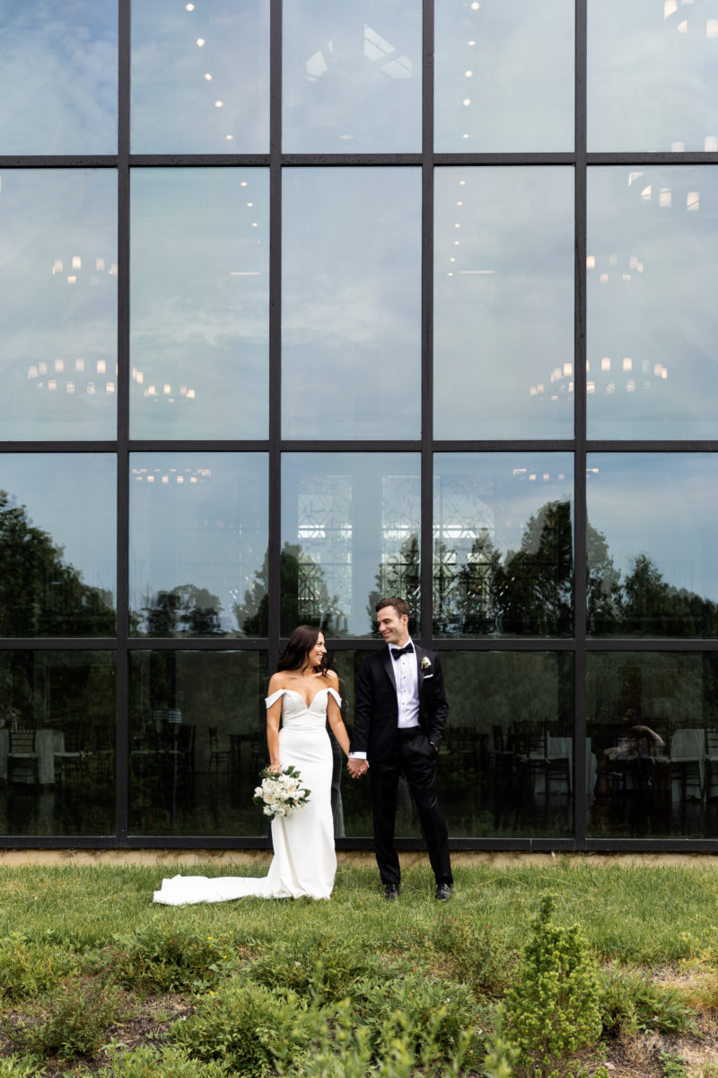 Bride and Groom pose in front of Farmhouse window