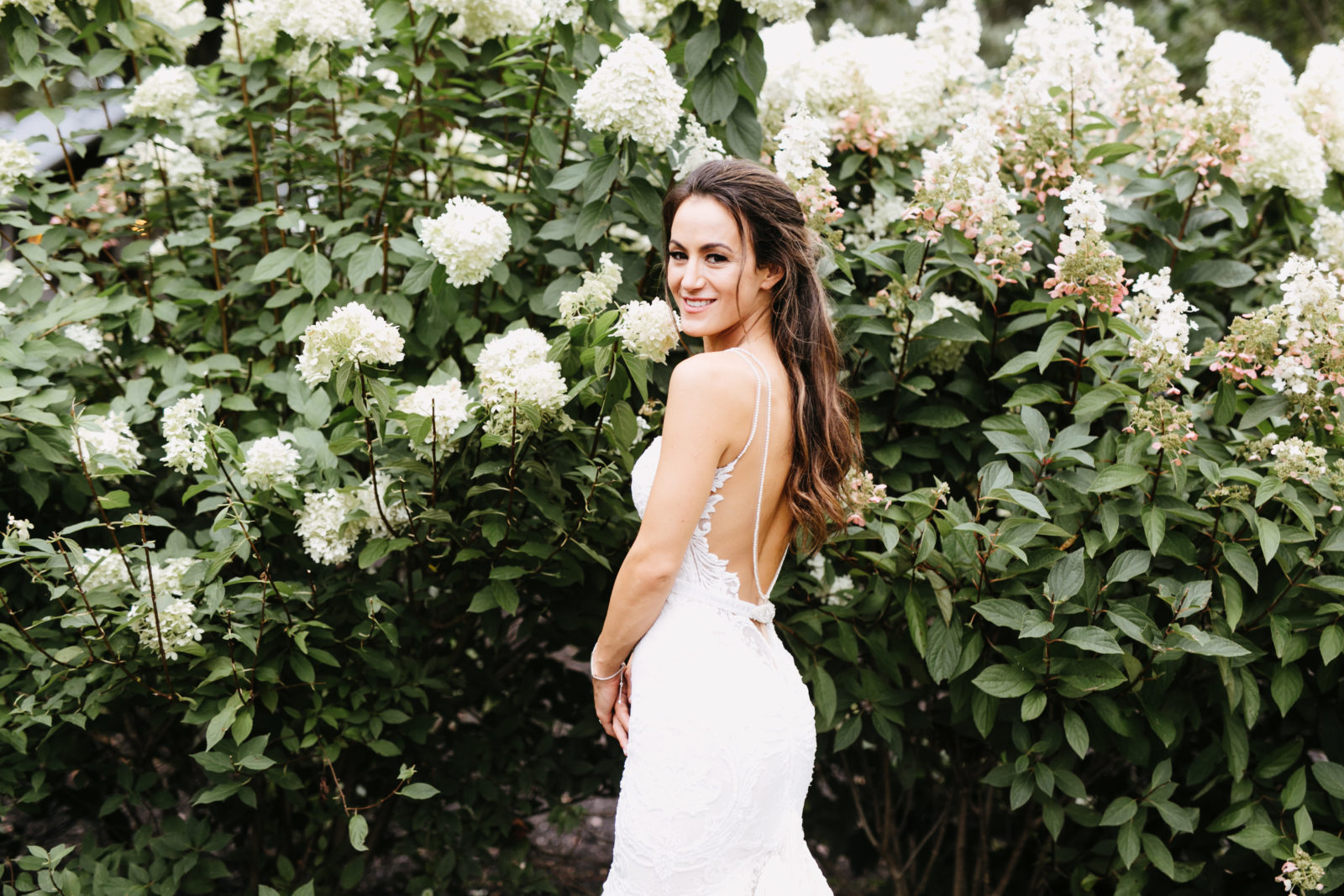 Bride poses in front of hydrangea garden