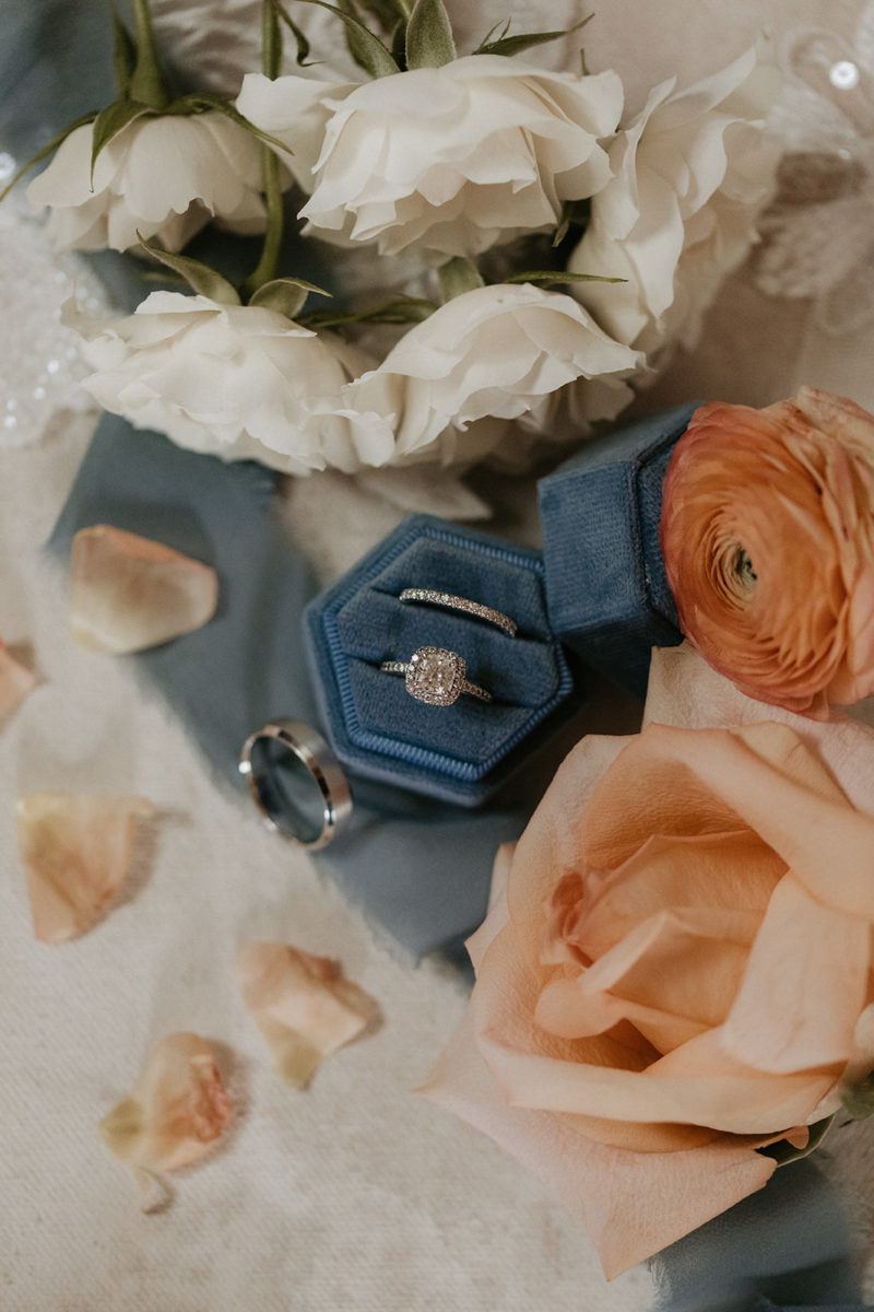 Wedding rings in blue ring boxes amongst flowers
