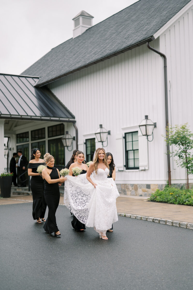 bridesmaids helping to carry the brides beautiful dress train to keep it dry and clean