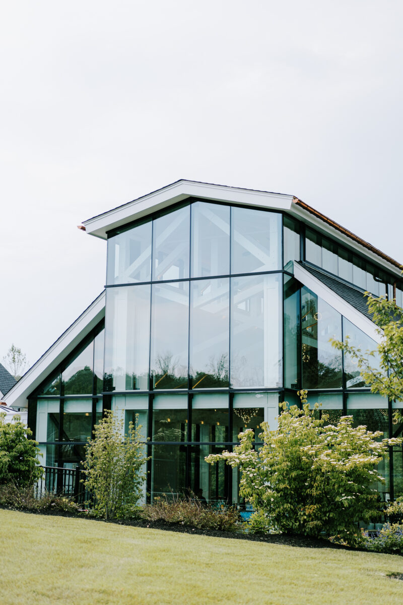 glass-enclosed conservatory surrounded by greenery and landscaping