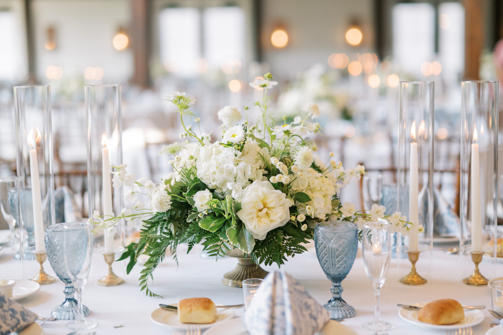 Romantic summer reception with blue water goblets, textured napkins, and candlelight at Crossed Keys Estate.