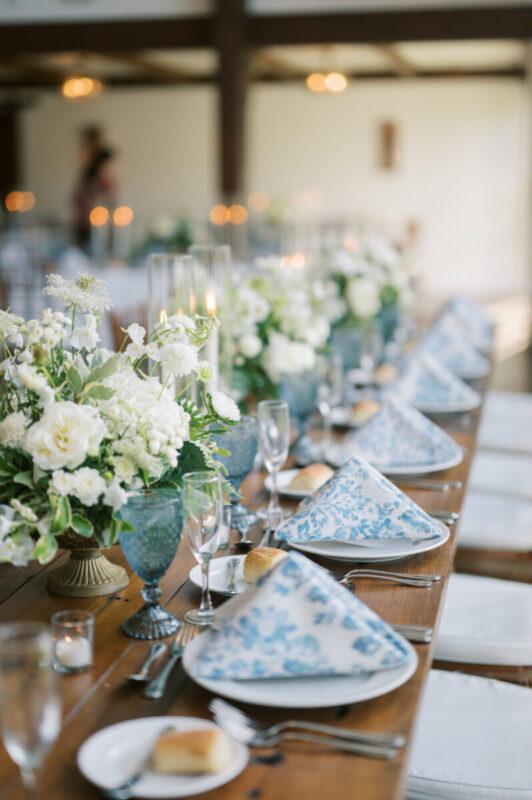 Romantic summer reception with blue water goblets, textured napkins, and candlelight at Crossed Keys Estate.