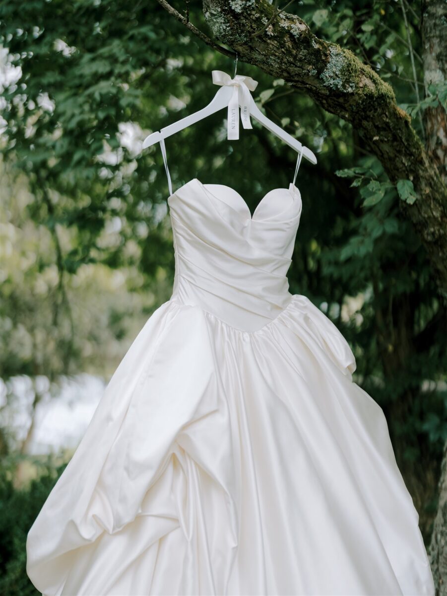 Iconic Devonne Pronovias Privée. Satin Princess Wedding Dress. Sleeveless bodice featuring a sweetheart neckline and flattering draping and cathedral train. Hanging from the natural greenery of the Crossed Keys Estate property.