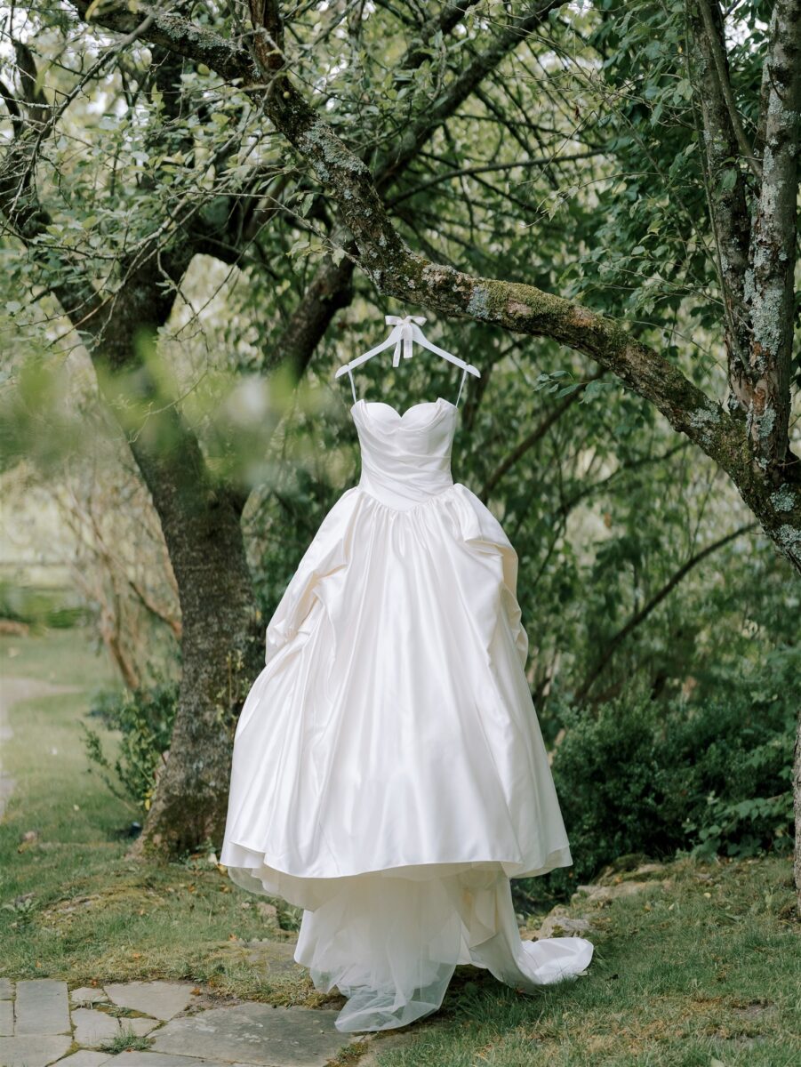 Iconic Devonne Pronovias Privée. Satin Princess Wedding Dress. Sleeveless bodice featuring a sweetheart neckline and flattering draping and cathedral train. Hanging from the natural greenery of the Crossed Keys Estate property.