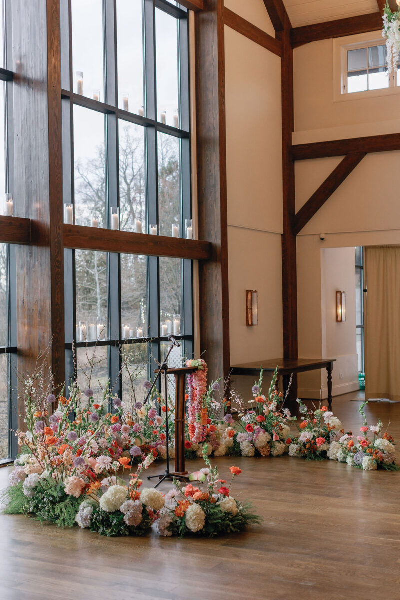 Bright pink, orange, and purple floral horseshoe arbor for Indian wedding ceremony with carnation and rose garlands