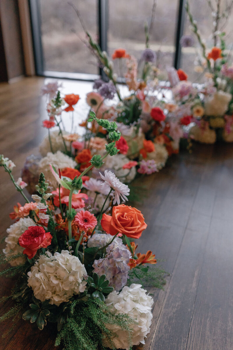 Bright pink, orange, and purple floral horseshoe arbor wedding ceremony