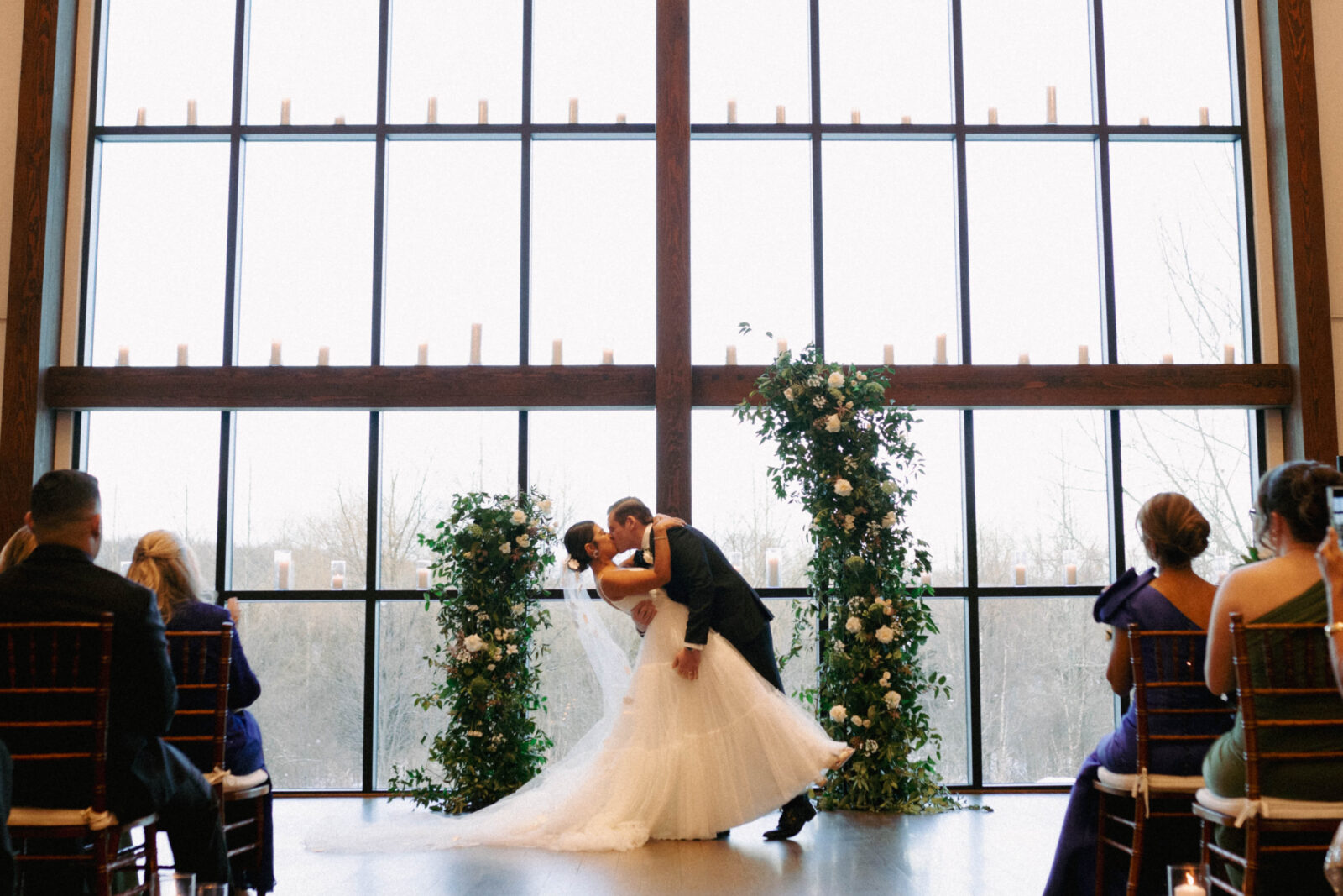 Golden light streaming through Farmhouse windows at Crossed Keys Estate as the newly married couple exchanges their first kiss.