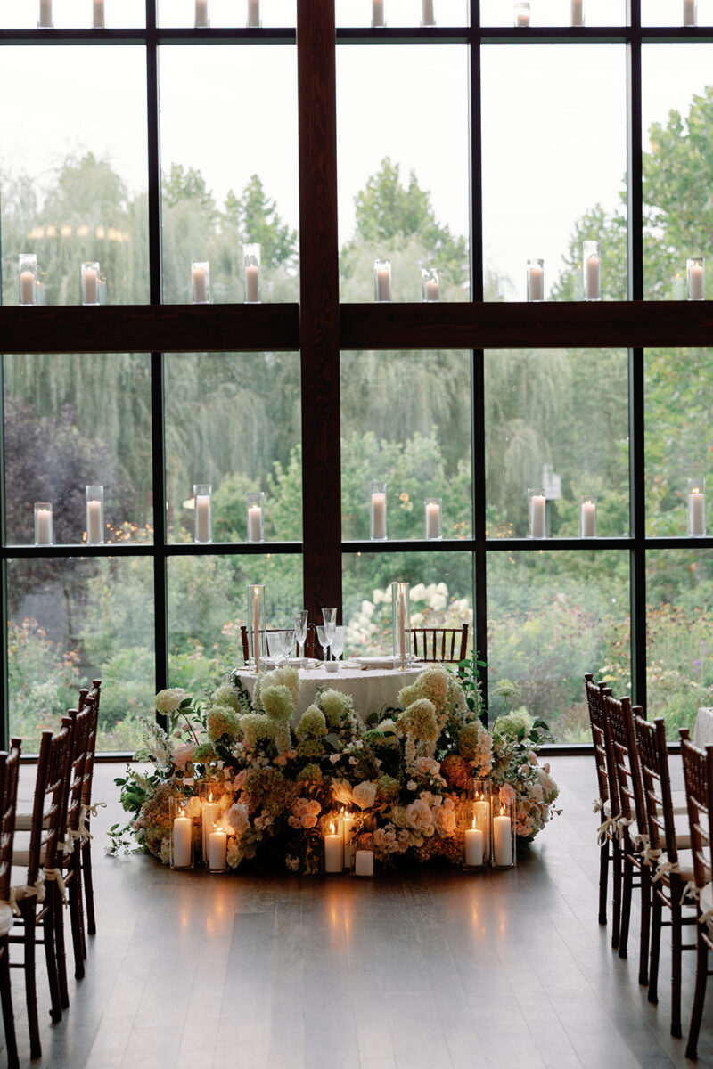 Sweetheart table with repurposed ceremony florals and pillar candles