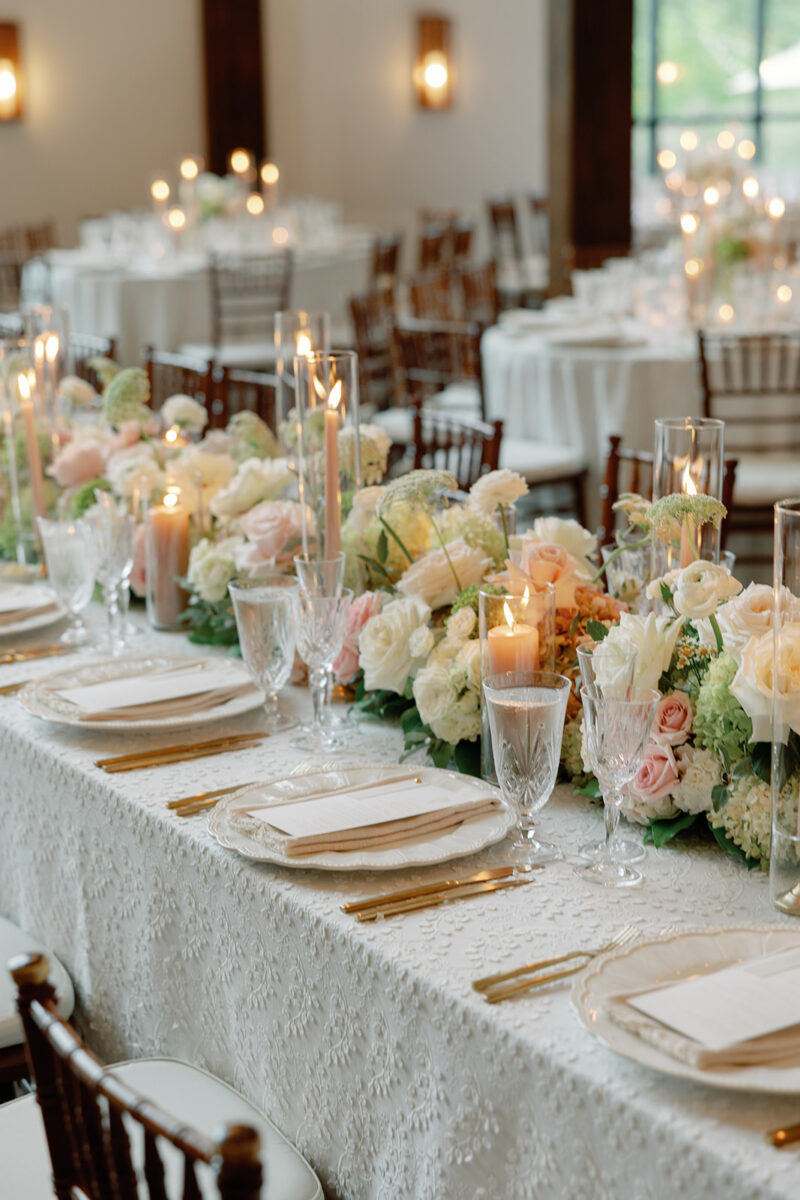 Lush floral runner with desert rose taper candles on farmhouse reception table