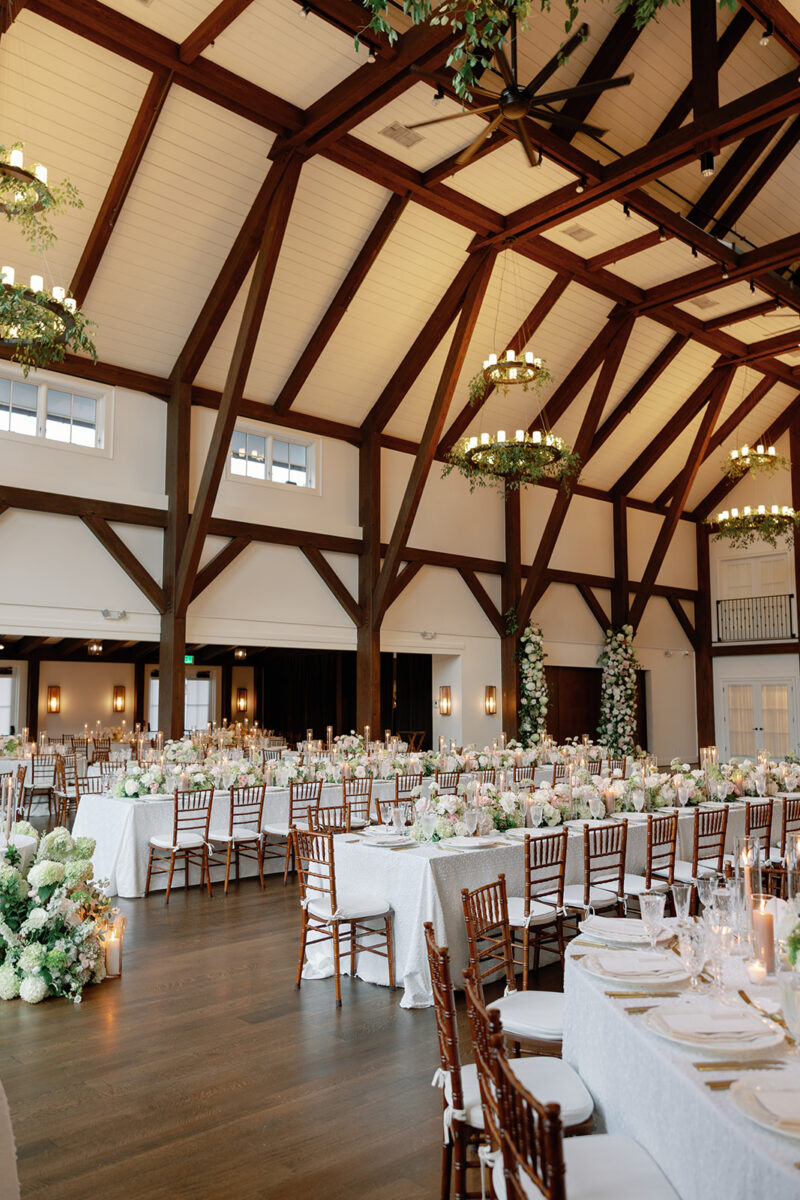 Stunning Farmhouse reception with vine-draped chandeliers, lush floral runners and beam florals
