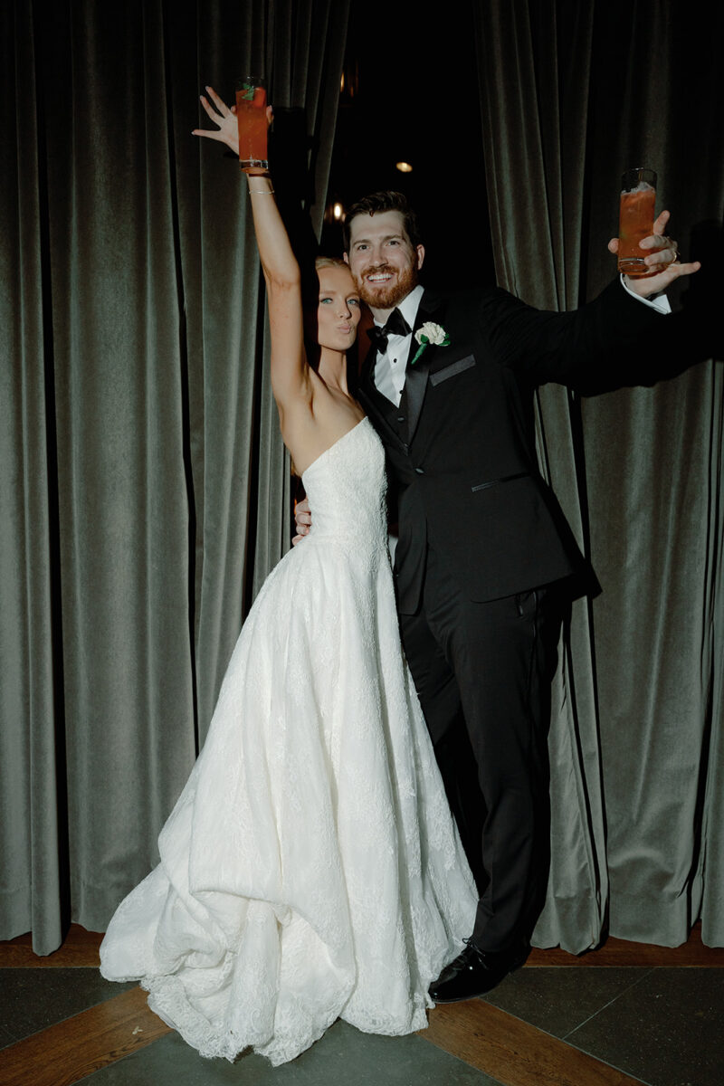 Couple posing with strawberry margarita signature cocktails. Reception cocktails