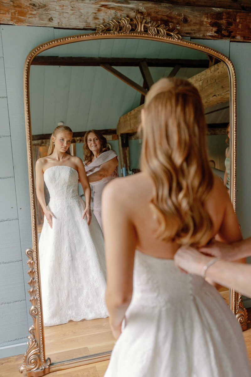 Mother of the bride helping the bride into her Anne Barge lace wedding gown in the Playhouse.