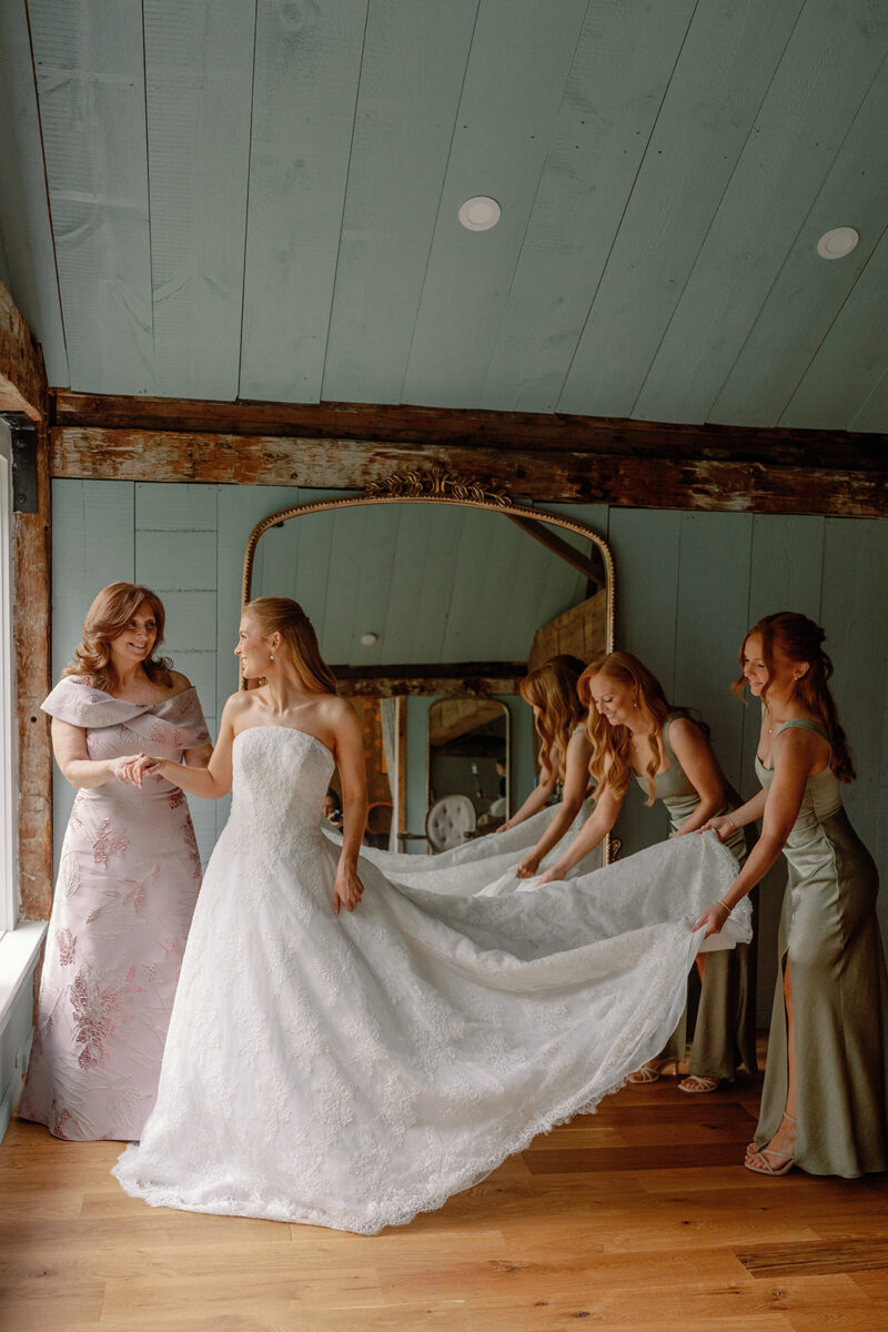 Mother of the bride and sisters helping the bride into her Anne Barge lace wedding gown in the Playhouse.