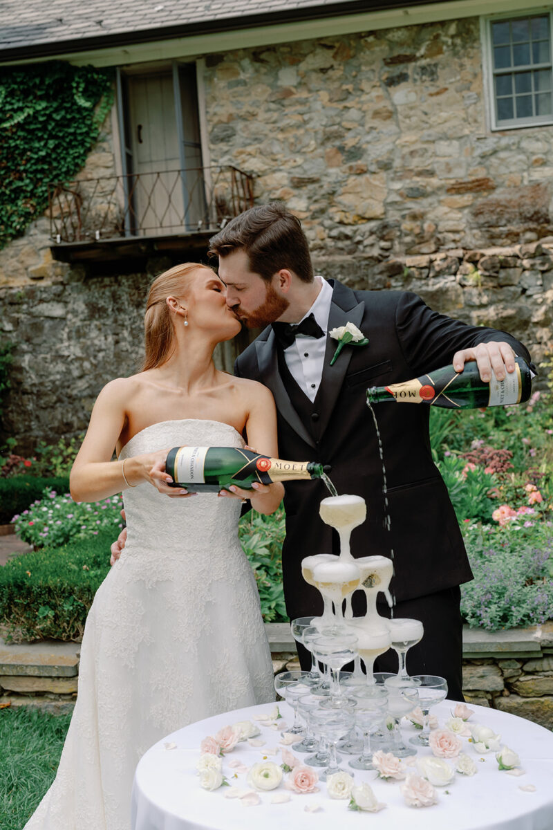 Bride and Groom pouring champagne before outdoor garden wedding ceremony