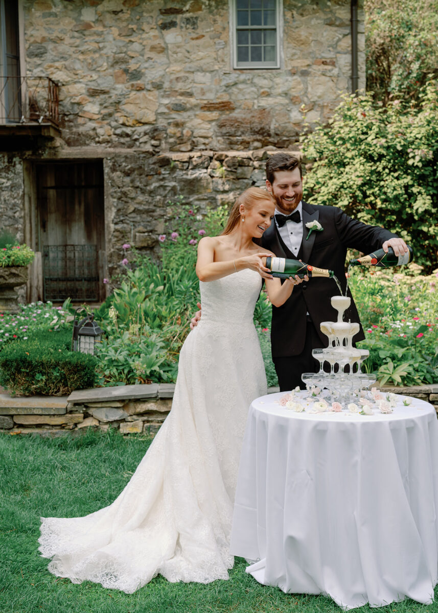 Bride and Groom pouring champagne before outdoor garden wedding ceremony