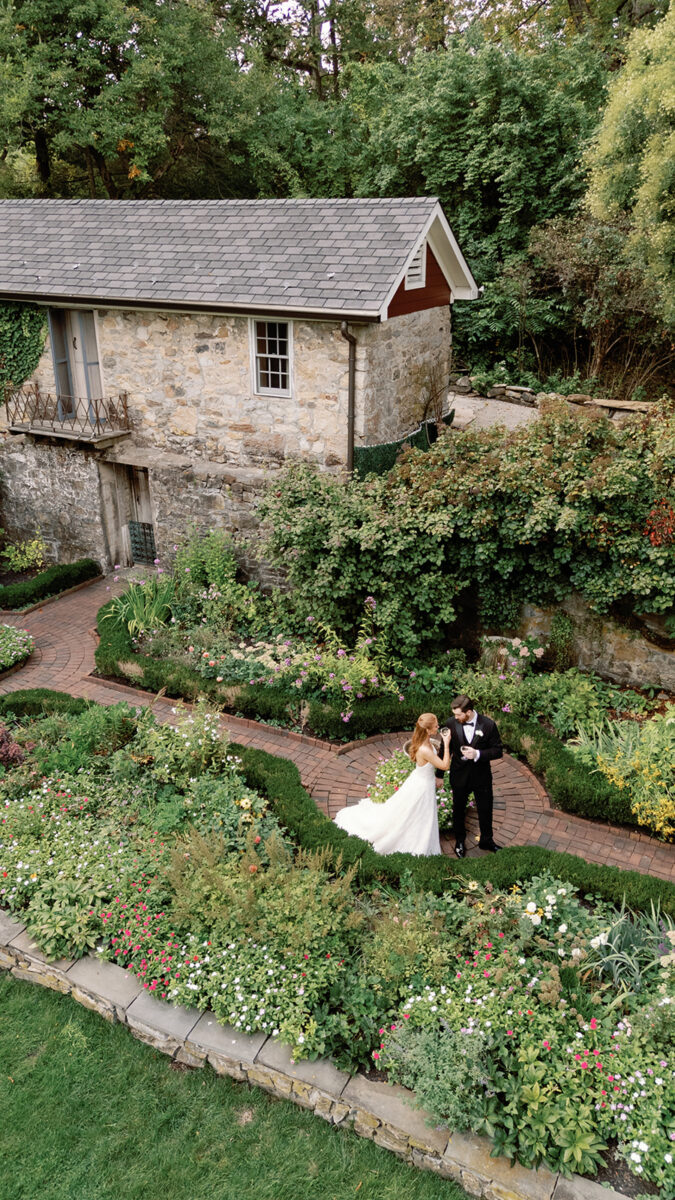 Drone portrait of bride and groom in the late summer September garden. Sipping champagne before their September garden wedding