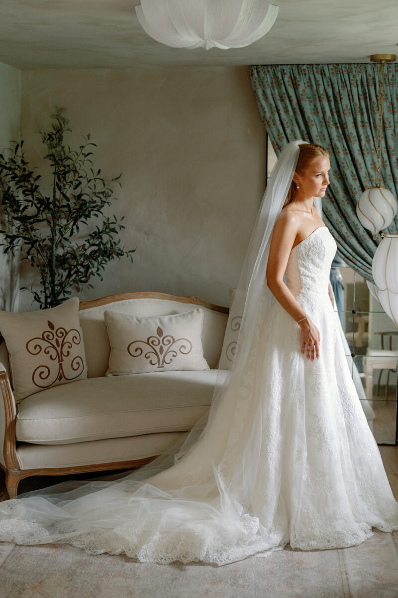 Bride in strapless lace Anne Barge gown with lace-edged veil before garden wedding