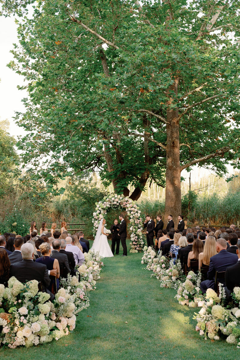 Couple exchanging vows beneath floral arbor at Crossed Keys Estate