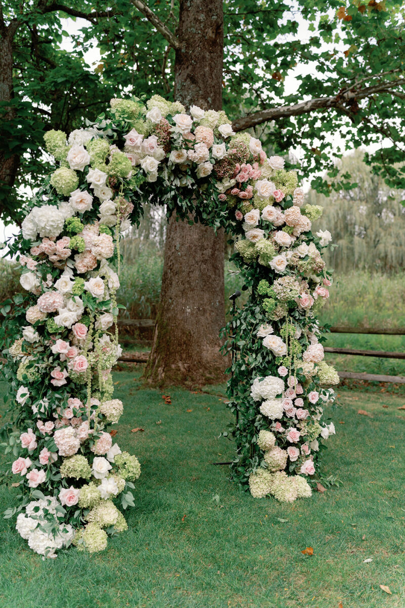 Organic floral ceremony arbor with hydrangeas and roses under oak trees