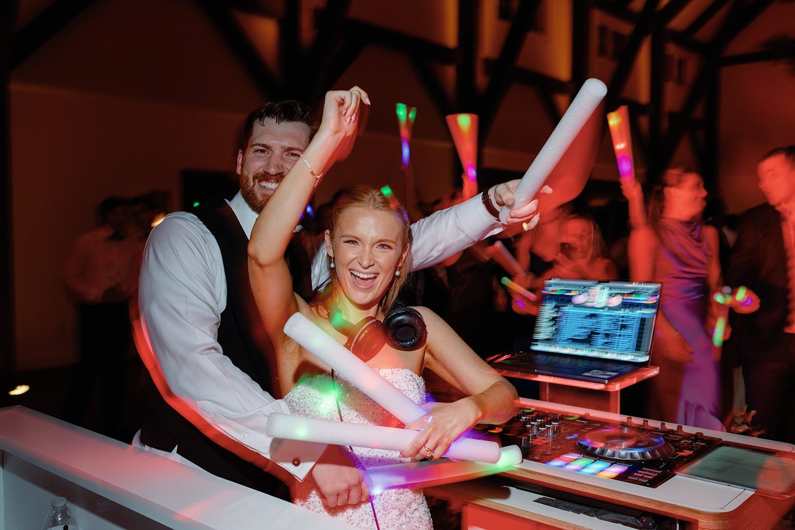 Bride and groom behind DJ booth hyping up guests on dance floor