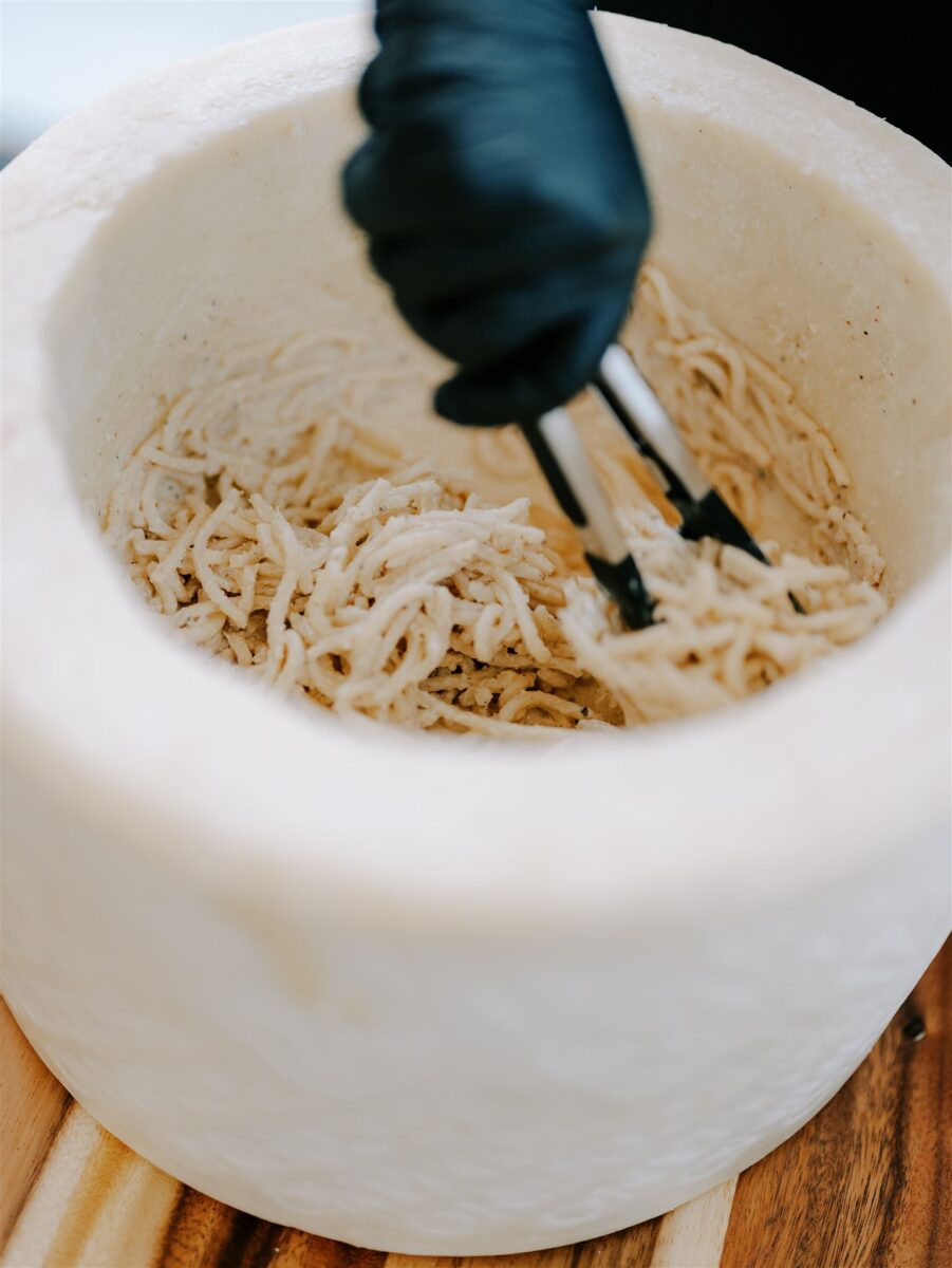 Caico e pepe pasta served in a cheese wheel with crushed black pepper.